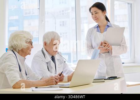 Gruppe professioneller Radiologen, die die Ergebnisse der MRT-Untersuchung während der Röntgenuntersuchung des Patienten im Sprechzimmer analysieren Stockfoto