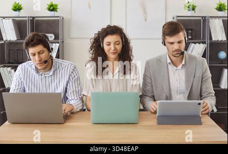 Porträt der Callcenter-Agenten im Headset, die mit einem Laptop arbeiten und mit Kunden kommunizieren Stockfoto