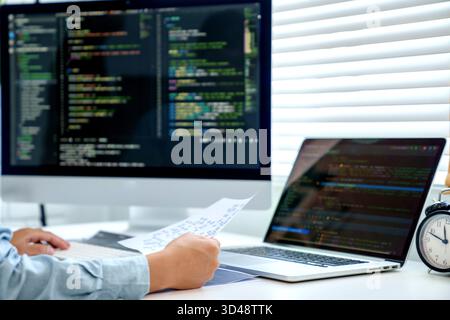 Programmierer schreibt Programmcode mit zwei Monitoren und arbeitet an einer neuen Software oder Hacker programmieren Software-Anwendungen im Büro || Modell veröffentlicht Stockfoto