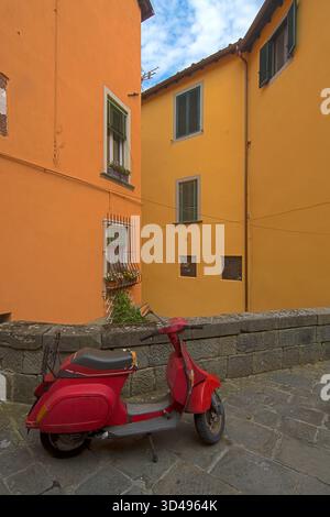 Szenen aus einer kleinen Stadt, Lucca in der Toskana, Italien mit einer roten Vespa und gelben Wänden Stockfoto