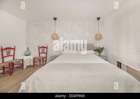 Nahaufnahme eines kleinen Schlafzimmers mit einem Einzelbett und grauer Plüschdecke, begleitet von einem schwimmenden Nachttisch und einer Glasvase mit einer einzelnen Sonnenblume Stockfoto