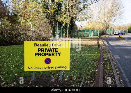 Gelbes Schild „Beaulieu Drive – Private Property – No Unauthorized Parking“ an einem grünen Straßenrand in England, auf dem private Zugangsbeschränkungen angegeben sind. Stockfoto