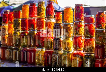 Bunte Gläser mit eingelegtem Gemüse, die auf einem Marktstand gestapelt sind, sorgen für eine lebendige Präsentation Stockfoto