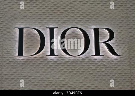 Beleuchtetes DIOR-Logo an einer strukturierten Wand. Minimalistisches Luxus-Branding in Nahaufnahme. Stockfoto