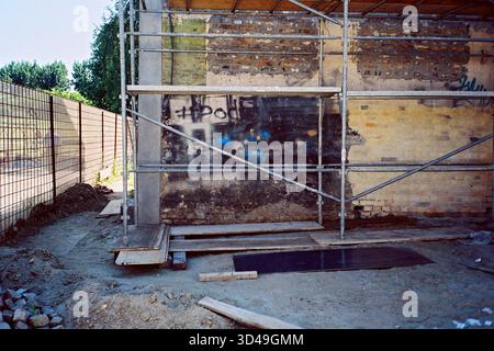 Graffiti-bedeckte Ecke in einem Backsteingebäude mit Gerüsten für Malerei, analoges Foto mit urbanem und strukturiertem Flair. Stockfoto