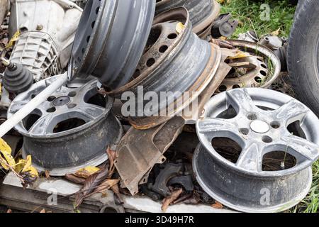 Alte Autofelgen mit Rost und Schmutz in einem Metallschrott. Konzept für industrielles Recycling, Abfallmanagement und Wiederverwendung von Autoteilen. Stockfoto
