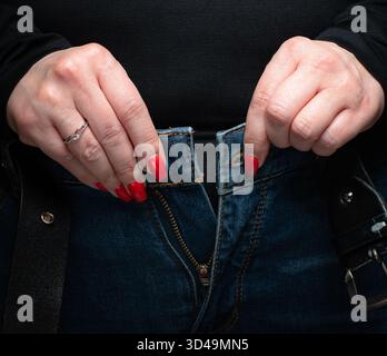 Nahaufnahme von Frauenhänden, die blaue Jeans aufknöpfen Stockfoto