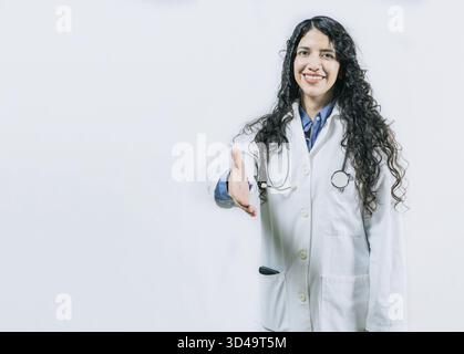 Lächelnde Ärztin, willkommen, isoliert. Lateinische Ärztin schüttelt die Hände vor der Kamera und gibt Gesten willkommen Stockfoto