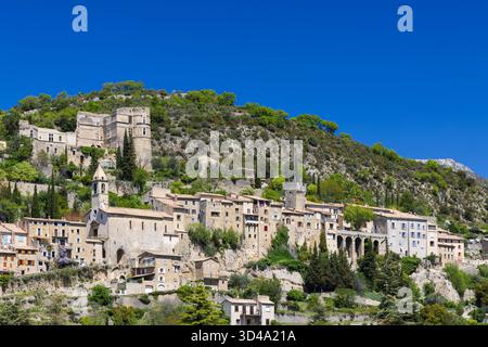 Historische Dorfgebäude, die sich an einem steilen Hügel vor einem klaren blauen Himmel festhalten Stockfoto