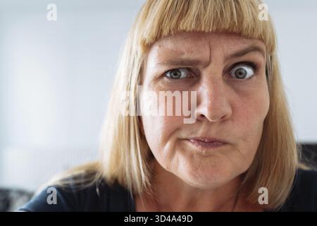 Blauäugig, attraktiv, Frau mittleren Alters, negative Emotionen im Gesicht, blond, grimmig, runzelnd, Augenbrauen heben, überrascht. Schaut in die Kamera, Communi Stockfoto