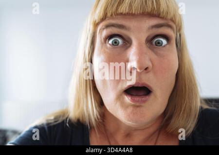Blauäugig, attraktiv, Frau mittleren Alters, negative Emotionen im Gesicht, blond, grimmig, runzelnd, Augenbrauen heben, überrascht. Schaut in die Kamera, Communi Stockfoto