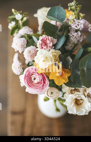 Blick von oben lebendiger und farbenfroher Blumenstrauß in einer weißen Vase auf einer Holzoberfläche aus nächster Nähe Stockfoto