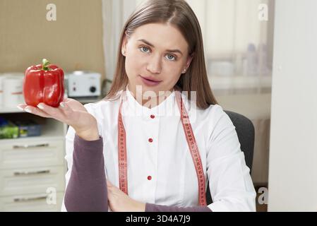 Schöne junge Ernährungsberaterin in weißer Uniform mit rotem Pfeffer Stockfoto