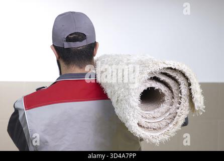 Rückansicht des Menschen mit einer Rolle Teppich auf einer Schulter Stockfoto