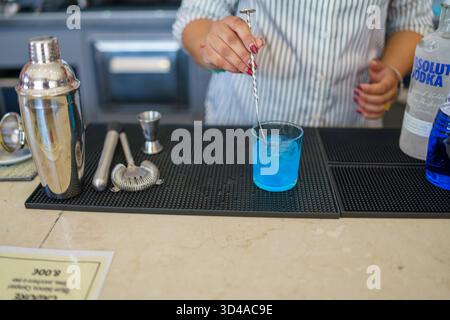 Crema, Italien - 25. August 2025 der erfahrene Barkeeper bereitet mit Barwerkzeugen und Zutaten auf Anhieb Einen erfrischenden Blauen Cocktail mit Eis zu Stockfoto