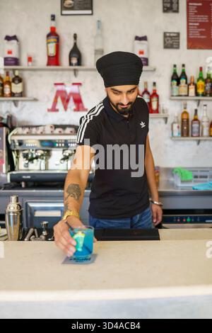 Crema, Italien - 25. August 2025 erfahrener Barkeeper, der einen lebhaften blauen Cocktail mit frischen Zutaten zubereitet und in einer modernen Bar mit professionellem Bevera-Ambiente eingerichtet wird Stockfoto