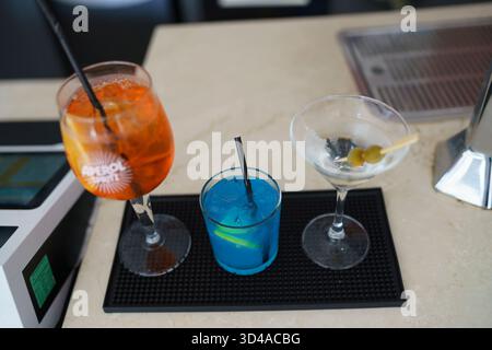 Crema, Italien - 25. August 2025 drei erfrischende, farbenfrohe Cocktails mit Eis und Garnituren an einer Bar, die in einer modernen Lounge oder serviert werden Stockfoto