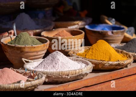 Natürliche Farbpigmente Pulver in Schüsseln auf Holztisch in Marrakesch, Marokko. Verschiedene lebhafte Farben, traditionelle Umgebung auf verschwommenem Hintergrund. Stockfoto