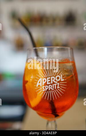 Crema, Italien - 25. August 2025 erfrischender Aperol Spritz-Cocktail mit Orangenscheibe und Strohhalm in einer Bar an einem sonnigen Tag Stockfoto