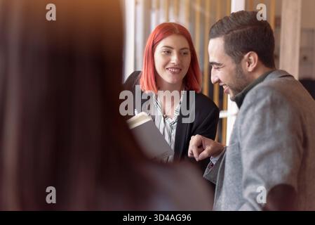 Eine Gruppe junger Fachkräfte, die ein freundliches Geschäftstreffen in einem modernen Café abhalten. Stockfoto
