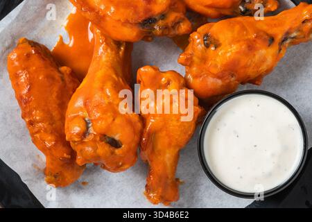 Nahaufnahme von sauren Büffelflügeln, serviert mit einer Tasse cremigem Ranch Dressing. Stockfoto