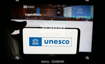 Stuttgart, Deutschland - 10-31-2025: Person in der Hand mit dem Logo der Organisation der Vereinten Nationen UNESCO auf dem Bildschirm vor der Webseite. Stockfoto