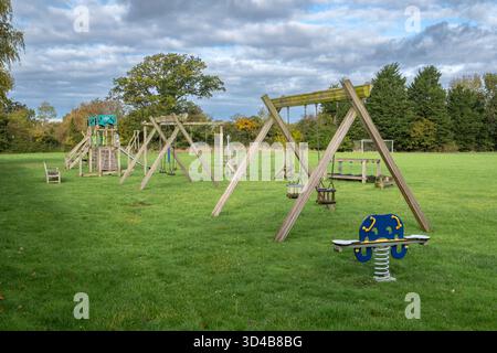 Leerer, verlassener Spielplatz mit Schaukeln, Rutsche, Klettergerüst und Kreisverkehr. Suffolk, Großbritannien. Stockfoto