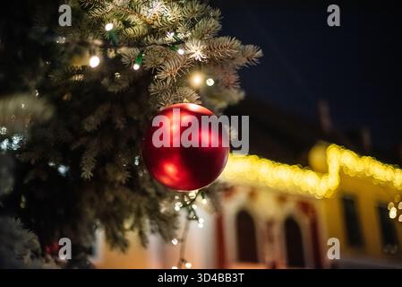 Rotes Weihnachtsschmuck auf einer Kiefer mit festlichen Lichtern bei Nacht Stockfoto