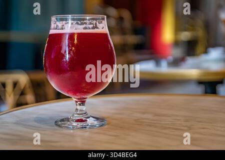 Ein Glas Himbeer-lambic-Bier in einem Restaurant im Freien mit verschwommenen Gebäuden in der Altstadt oder Vieille Ville in Nizza, Südfrankreich Stockfoto