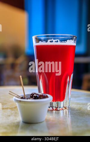 Ein Glas Himbeer-lambic-Bier in einem Restaurant im Freien mit verschwommenen Gebäuden in der Altstadt oder Vieille Ville in Nizza, Südfrankreich Stockfoto