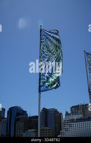 Darling Harbour Banner mit einem blauen und grünen abstrakten Muster und der Skyline der Stadt im Hintergrund unter klarem Himmel. Stockfoto