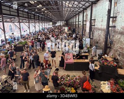 Carriageworks Farmers Market in Sydney, Australien, ist voll von Käufern, die verschiedene Stände erkunden, die frische Produkte, Blumen und lokale Produkte anbieten Stockfoto