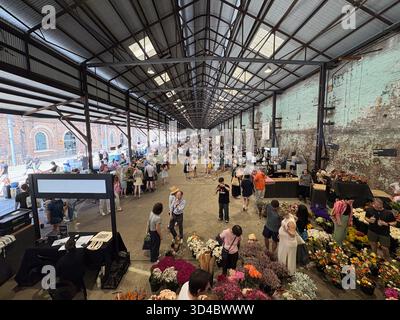 Carriageworks Farmers Market, Sydney, Australien. Geschäftiger Indoor-Markt mit vielen Leuten, die an Ständen frische Produkte und Blumen verkaufen, in einem umgestalteten Gebäude Stockfoto