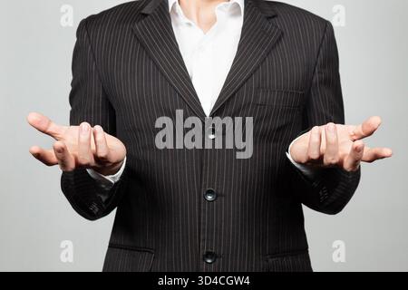 Nah an einem Geschäftsmann im Anzug, der einen verwirrten Ausdruck mit Händen und weißem Hintergrund macht Stockfoto