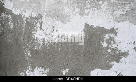 Alte Betonwand mit abblätternder weißer Farbe. Verwitterter rauer Untergrund mit Rissen und Flecken. Stockfoto