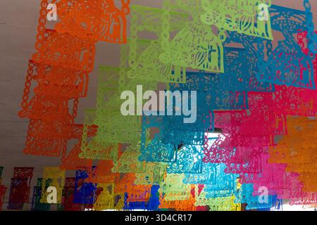 Eine bunte Ausstellung von Papierlaternen hängt an einer Wand. Die Farben sind hell und lebendig. Mexikanischer Tag der Toten Tradition, Opfer, Essen, Farben, d Stockfoto