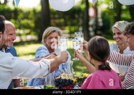 Generationenübergreifende Familientoasten während einer Grillparty im Freien. Stockfoto