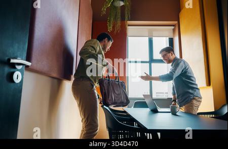 In einem modernen Büro begrüßen zwei Erwachsene Männer vor einem Meeting. Die Umgebung spiegelt Produktivität und Professionalität des Unternehmens wider und betont die Zusammenarbeit Stockfoto