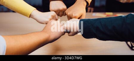 Ein lebendiger Moment der Zusammenarbeit, in dem fünf Hände in einem Faustschlag aufeinander treffen, symbolisieren Einheit und Teamarbeit in einer professionellen Umgebung, zeigen Unterstützung und Stockfoto