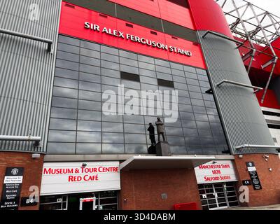 Manchester, Großbritannien - 30. September 2025: Rote und graue Fassade des Stadions mit Glaswand, Statue und Eingang zum Museumscafé in Manchester Stockfoto