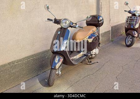 Vallila, Helsinki, Finnland - 13. August. 2025: Schwarzer Vespa Primavera-Roller parkt auf der Straße in Helsinki. Stockfoto