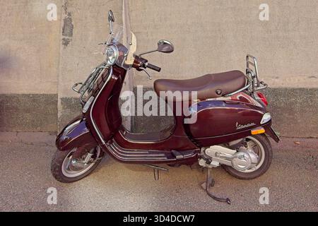 Vallila, Helsinki, Finnland - 13. August. 2025: Der Vespa LX-Roller parkt auf dem Bürgersteig vor der Mauer. Stockfoto