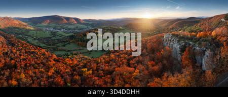 Berge bei Sonnenuntergang. Landschaft mit Hügeln, Orangenbäumen und Gras im Herbst, farbenfroher Himmel mit goldenen Sonnenstrahlen. Saisonale Naturszene Stockfoto