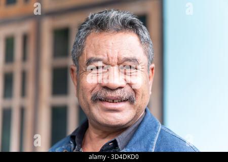 Ein warmes, freundliches Porträt eines glücklichen älteren asiatischen Mannes, der in die Kamera lächelt. Tragen Sie eine Jeansjacke. Stockfoto