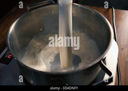 Milch auf der Waage in die Pfanne gießen. Stockfoto