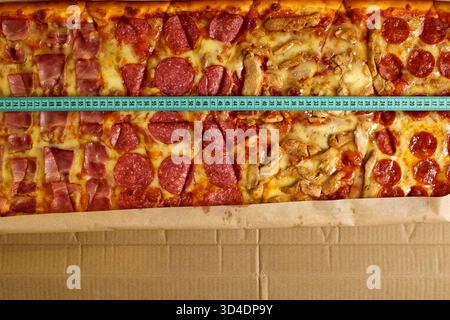 Lange große Würstchen-Pizza. Messen Sie die Pizzabänge mit einem Maßband Stockfoto