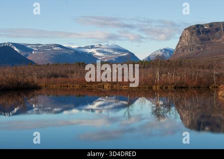 Laukkujärvi-See in der Nähe von Nikkaluokta, Lappland, Nordschweden, im Spätherbst mit schneebedeckten Kebnekaise-Bergen, die sich im Wasser spiegeln Stockfoto
