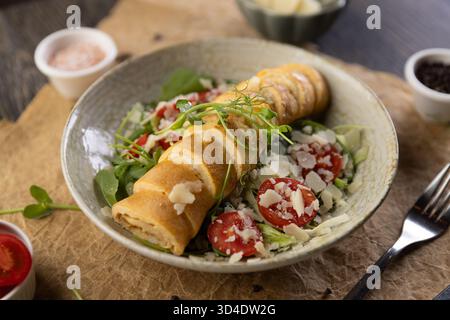 Roll-Omelette gefüllt mit Käse serviert auf frischem Salat, Frühstücksmenü im Restaurant Stockfoto