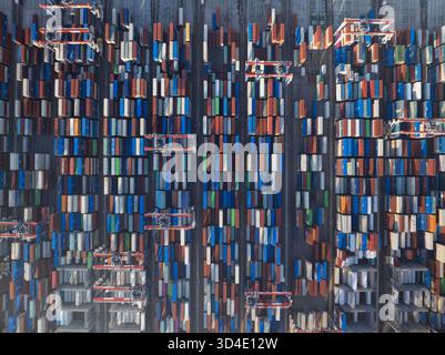 Die Luftaufnahme eines Meeres aus gestapelten, vielfarbigen Schiffscontainern, wie riesige Bausteine, schafft eine industrielle Landschaft mit Muster und Textur. Stockfoto