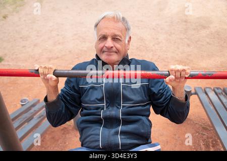 Senior Mann, der eine Übung in einem Outdoor-Fitness-Park mit Schwerpunkt auf seinem Wohlbefinden durchführt Stockfoto